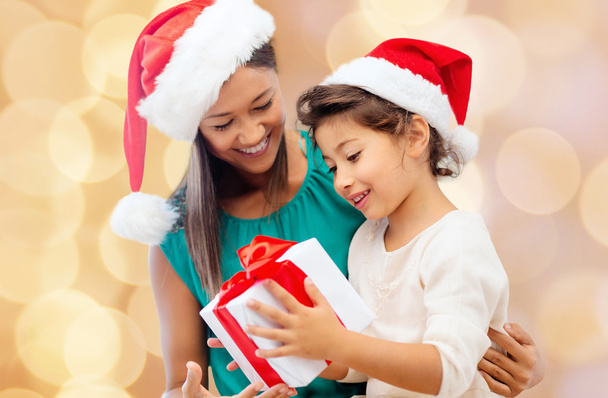 happy mother and girl in santa hats with gift box - Фото, зображення