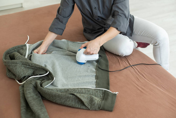 Dispositif sans fil pour nettoyer les tricots contre les peluches. La femme enlève la peluche du pull. - Photo, image