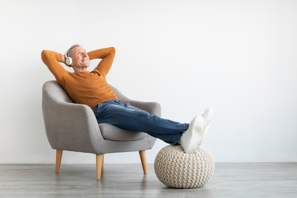 Rauhallinen kypsä mies ottaa levätä kotona kuunnellen musiikkia - Valokuva, kuva