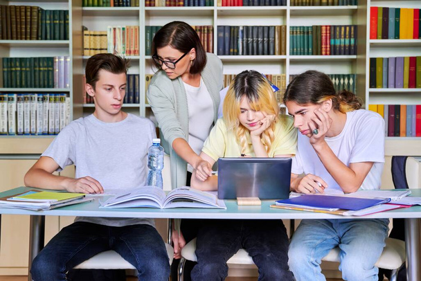 Group of teenage students studying in library class with female teacher mentor - Photo, Image