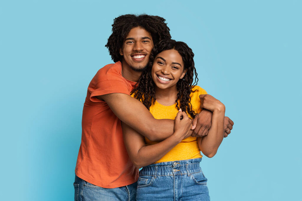 Loving black man and woman hugging on blue background - Photo, Image