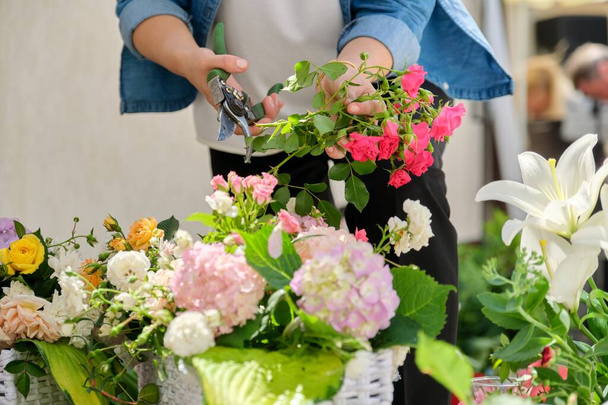 Woman florist making flower arrangement in basket outdoor. - Foto, Imagen