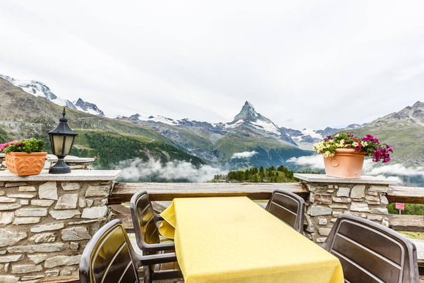 beautiful view of restaurant surround by mist lake and mountains with empty table - Photo, Image
