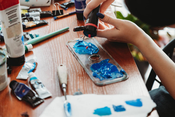 Close up of female artist hands mixing paint in her art studio - Foto, Imagen