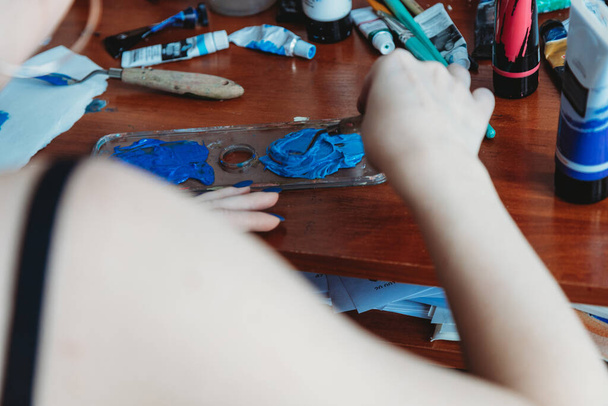 Close up of female artist hands mixing paint in her art studio - Foto, afbeelding