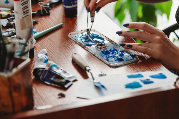 Close up of female artist hands mixing paint in her art studio - Foto, Bild