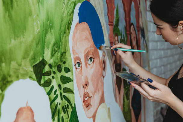 Pretty female artist painting with a brush in her art studio - Fotografie, Obrázek