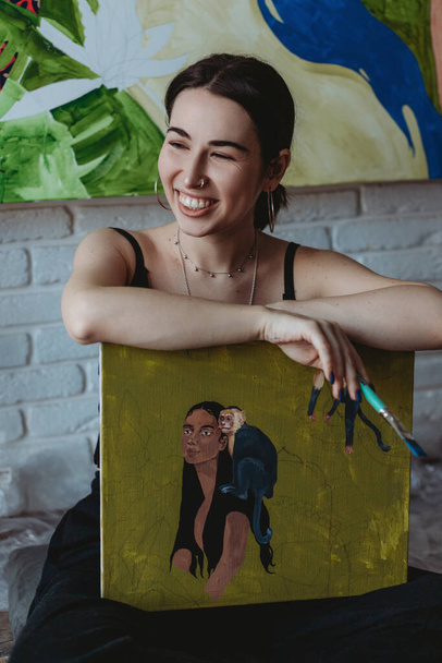 Pretty female artist with painting and brush in her art studio - Foto, Bild
