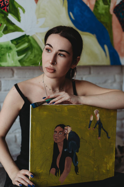 Pretty female artist with painting and brush in her art studio - Valokuva, kuva