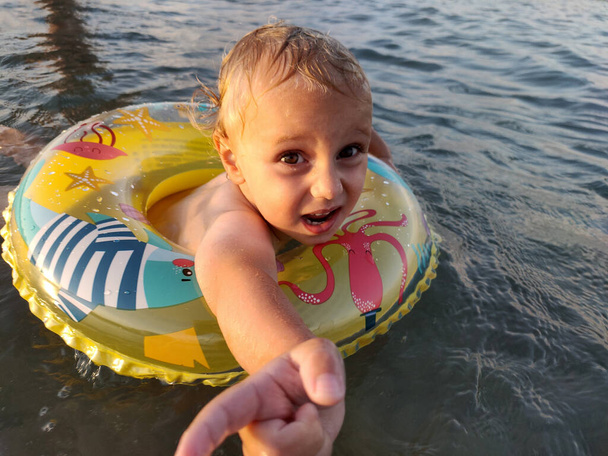 Un enfant malheureux dans la mer avec un anneau gonflable. - Photo, image