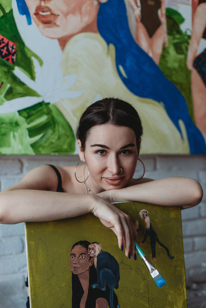 Pretty female artist with painting and brush in her art studio - Photo, Image