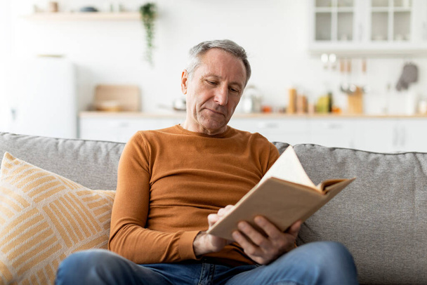 Portrait of mature man reading book at home - Foto, afbeelding
