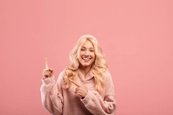 Portrét šťastné ženy ukazující dvěma prsty na volné místo, reklama na text nebo promo, růžové pozadí - Fotografie, Obrázek