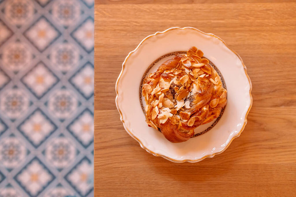 Ώρα για πρωινό. Γλυκό κέικ με κρέμα, αμύγδαλα σε ένα όμορφο πιάτο σε ξύλινο τραπέζι - Φωτογραφία, εικόνα