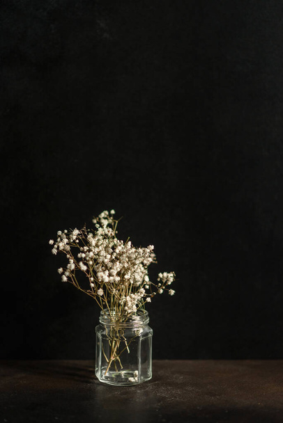 Beautiful twigs of dry gypsophile in a glass can on a dark concrete background - Photo, Image