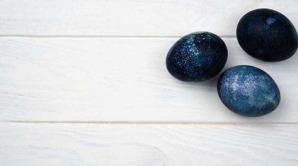 Easter eggs painted with natural dye in blue on the white wooden background. Banner. Close-up. Top view. Place for text. - Photo, Image