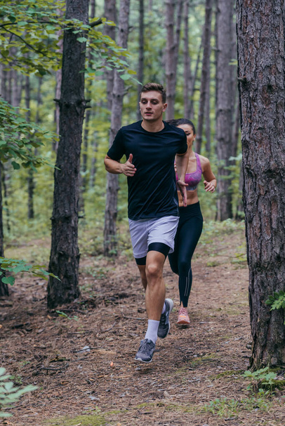 若い運動カップルが森の中で屋外で走っています - 写真・画像