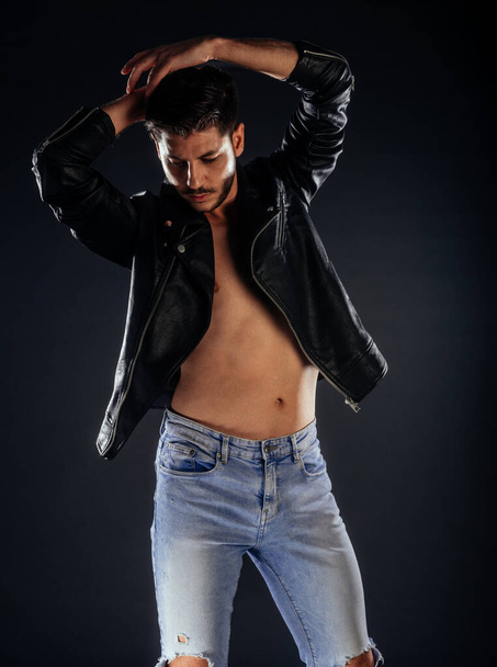 Прохолодний без сорочки хлопець у стильній шкіряній куртці та синіх джинсових штанях
 - Фото, зображення