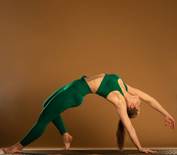 Attractive and beautiful young girl is doing the chakrasana pose - Fotó, kép