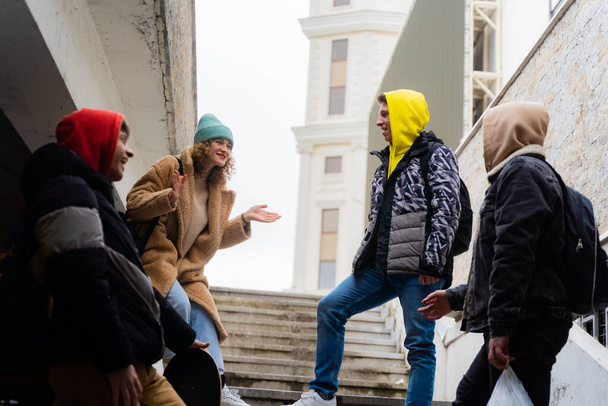 Grupa niesamowitych i atrakcyjnych przyjaciół prowadzi dyskusję na schodach śmiejąc się razem - Zdjęcie, obraz