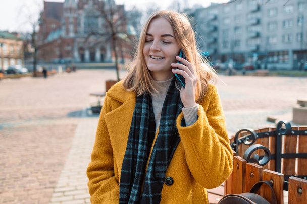Kaunis hymyilevä 30s nainen matkapuhelimella kävely aurinko kadulla - Valokuva, kuva