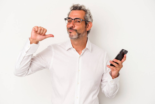 Hombre de negocios caucásico de mediana edad sosteniendo un teléfono móvil aislado sobre fondo blanco se siente orgulloso y seguro de sí mismo, ejemplo a seguir. - Foto, imagen