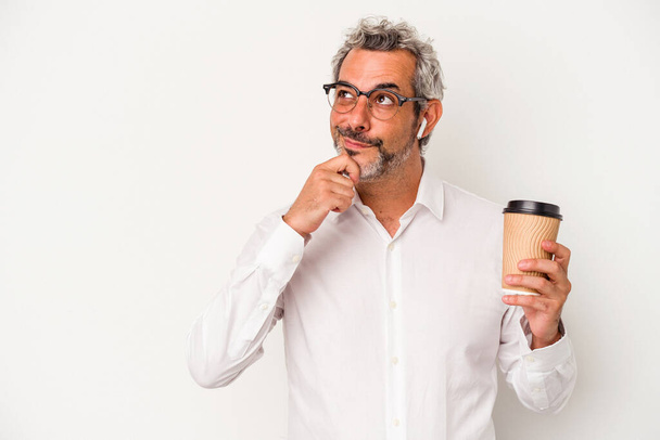 Keski-ikä liikemies tilalla take away kahvia eristetty valkoisella pohjalla etsivät sivuttain epäilyttäviä ja skeptinen ilme. - Valokuva, kuva