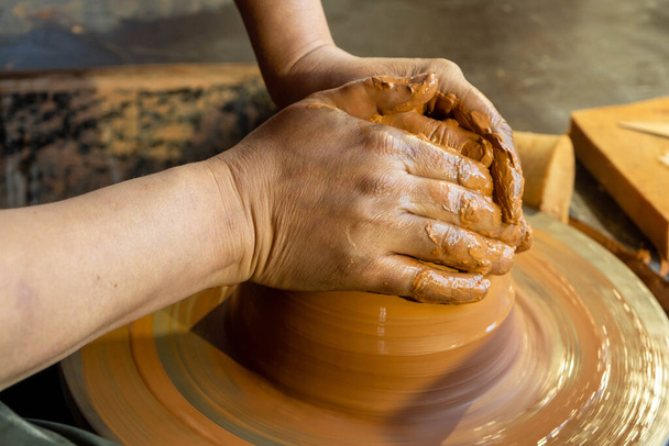 Hände eines Töpfers bei der Arbeit. Töpfer stellt Keramikbecher auf der Töpferscheibe her - Foto, Bild