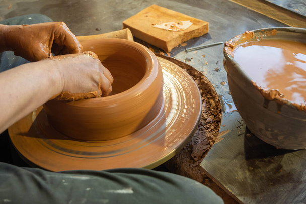hands of a potter, creating an earthen jar on the circle. - Fotografie, Obrázek