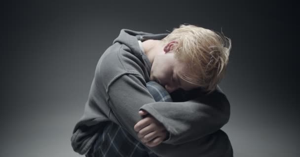 Giovane ragazzo depressivo si abbraccia mentre piange e pensa - Filmati, video