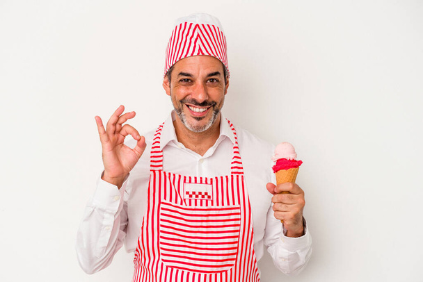 Edad media caucásico fabricante de hielo caucásico hombre sosteniendo un helado aislado sobre fondo blanco alegre y confiado mostrando gesto ok. - Foto, Imagen