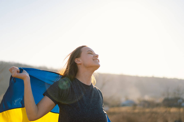 Woman holding a yellow and blue flag of Ukraine in outdoors - Foto, afbeelding