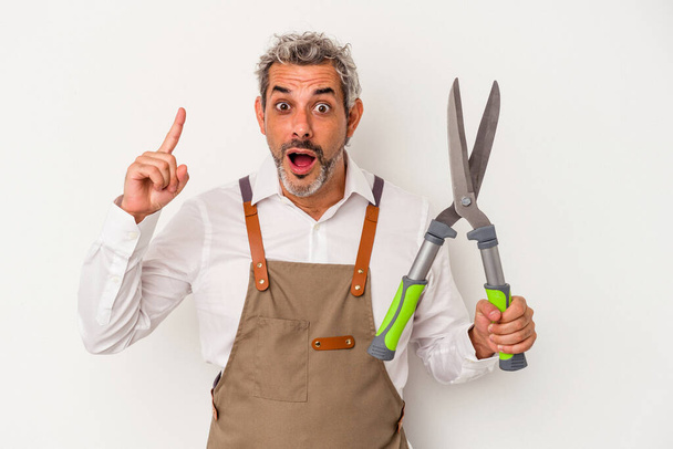 Middle age gardener man holding a scissors isolated on white background  having an idea, inspiration concept. - Фото, зображення