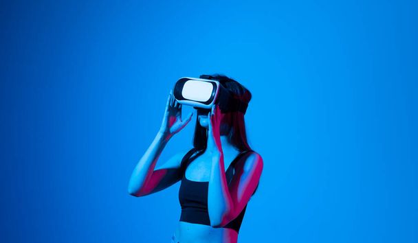 Smile happy woman getting experience using vr-headset glasses of virtual reality much gesticulating hands on gray background. Girl spend shes time in metaverse. - Fotó, kép