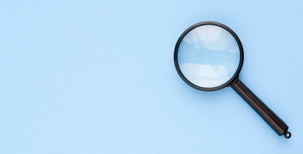 Black magnifier on a blue background. - Photo, image