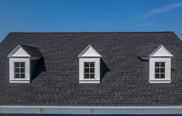 Close-up zicht op drie witte dakramen op een klassiek dak met blauwe lucht achtergrond - Foto, afbeelding