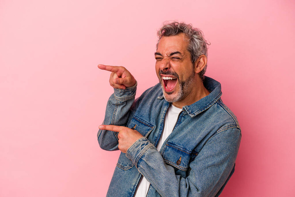 Middle age caucasian man isolated on pink background  excited pointing with forefingers away. - 写真・画像