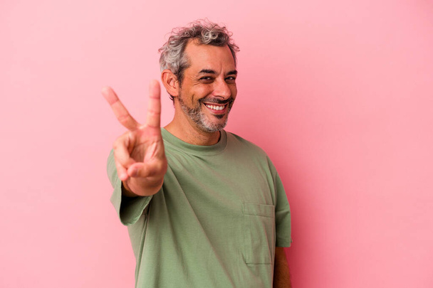 Middelbare leeftijd blanke man geïsoleerd op roze achtergrond vreugdevol en zorgeloos tonen van een vrede symbool met vingers. - Foto, afbeelding