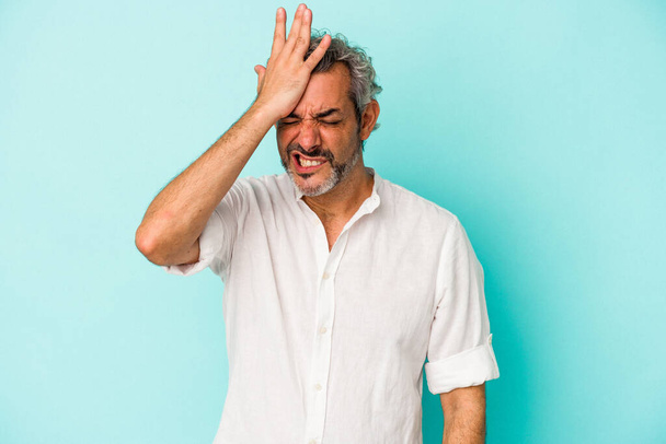 Middle age caucasian man isolated on blue background  forgetting something, slapping forehead with palm and closing eyes. - Photo, image