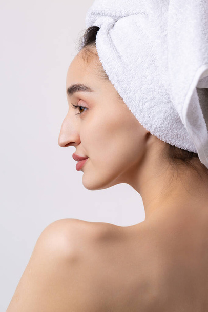 Beautiful girl with thick eyebrows and perfect skin at white background, towel on head, beauty photo. - Φωτογραφία, εικόνα