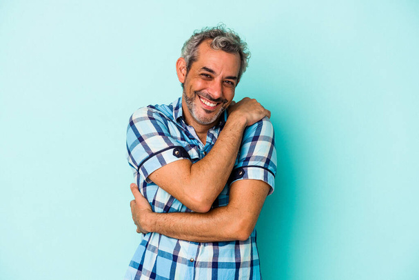 Middle age caucasian man isolated on blue background  hugs, smiling carefree and happy. - Foto, afbeelding