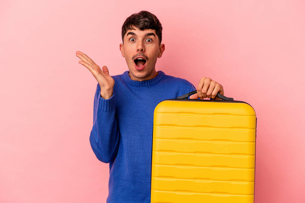 Young mixed race man going to travel isolated on pink background surprised and shocked. - Fotoğraf, Görsel