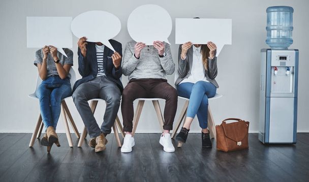 Tell us a little more about yourself. Shot of a diverse group of businesspeople holding up speech bubbles while they wait in line. - Photo, Image