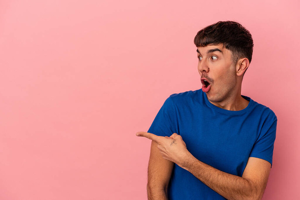 Joven hombre de raza mixta aislado en puntos de fondo rosa con el dedo pulgar lejos, riendo y sin preocupaciones. - Foto, Imagen