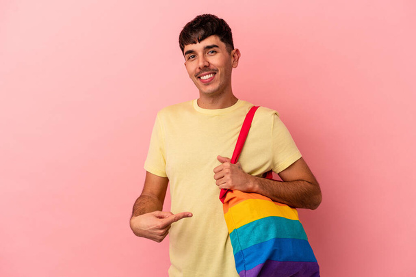 Giovane uomo razza mista indossa borsa LGTB isolato su sfondo rosa - Foto, immagini