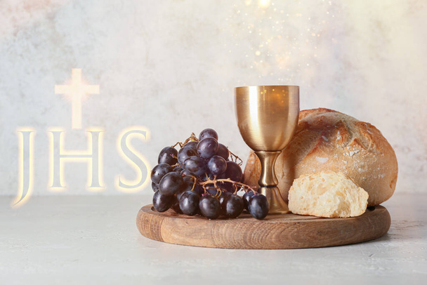 Chalice of wine with grapes and bread on light background. Holy Communion concept - 写真・画像