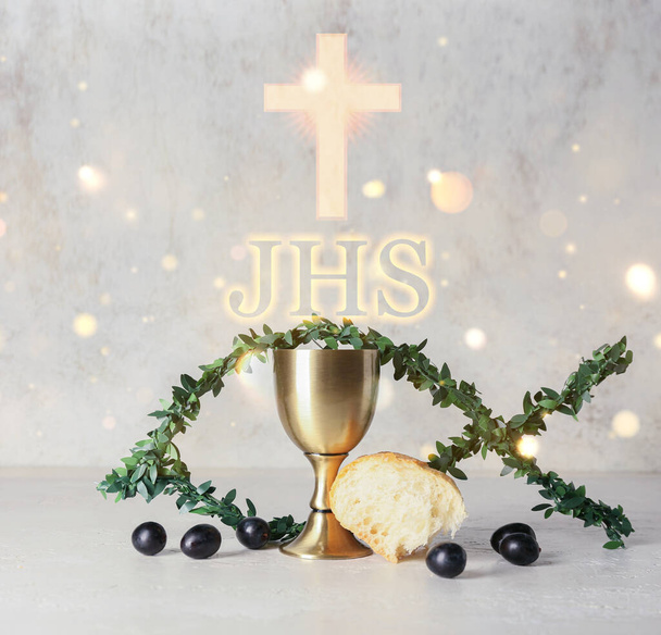 Chalice of wine with bread and fish made of branches on light background. Holy Communion concept - Photo, Image