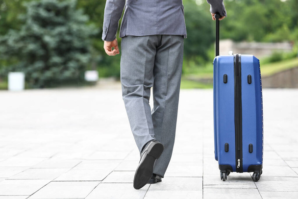 Junger Geschäftsmann mit blauem Koffer spaziert ins Freie - Foto, Bild