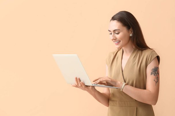 Pretty young businesswoman using laptop on beige background - Photo, Image