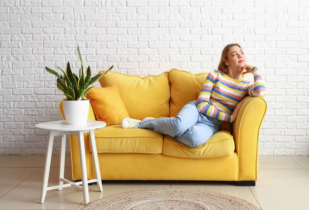 Ładna młoda kobieta relaksuje się na kanapie w domu - Zdjęcie, obraz